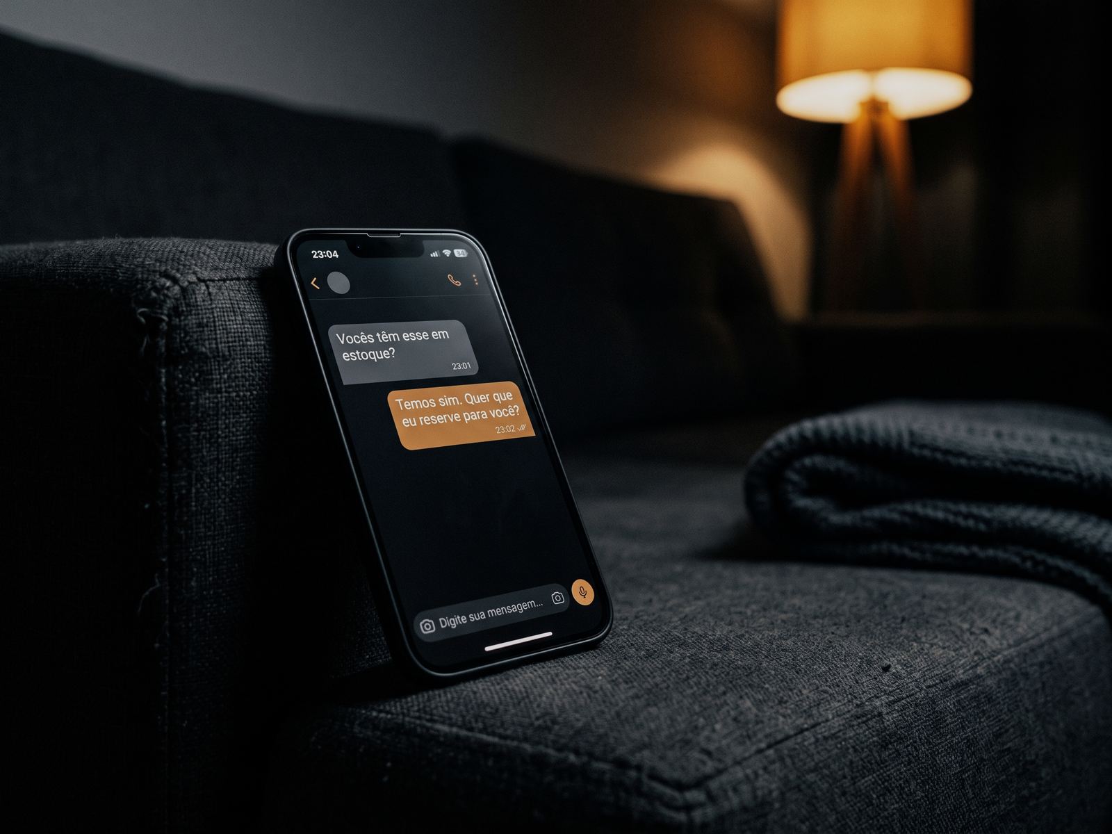 Celular sobre o braço de um sofá à noite, com a pergunta de um cliente respondida um minuto depois